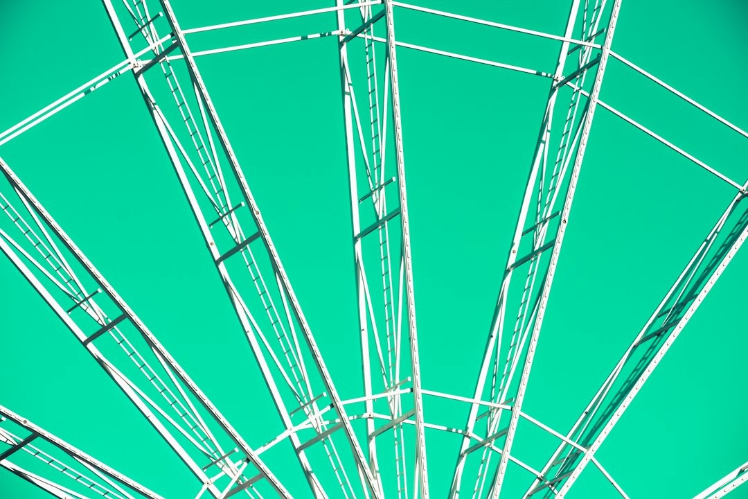 White metal Ferris wheel spokes against a bright teal sky.